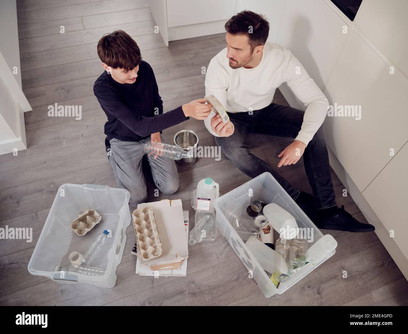Père et fils séparant les déchets en boîtes de recyclage Banque D'Images