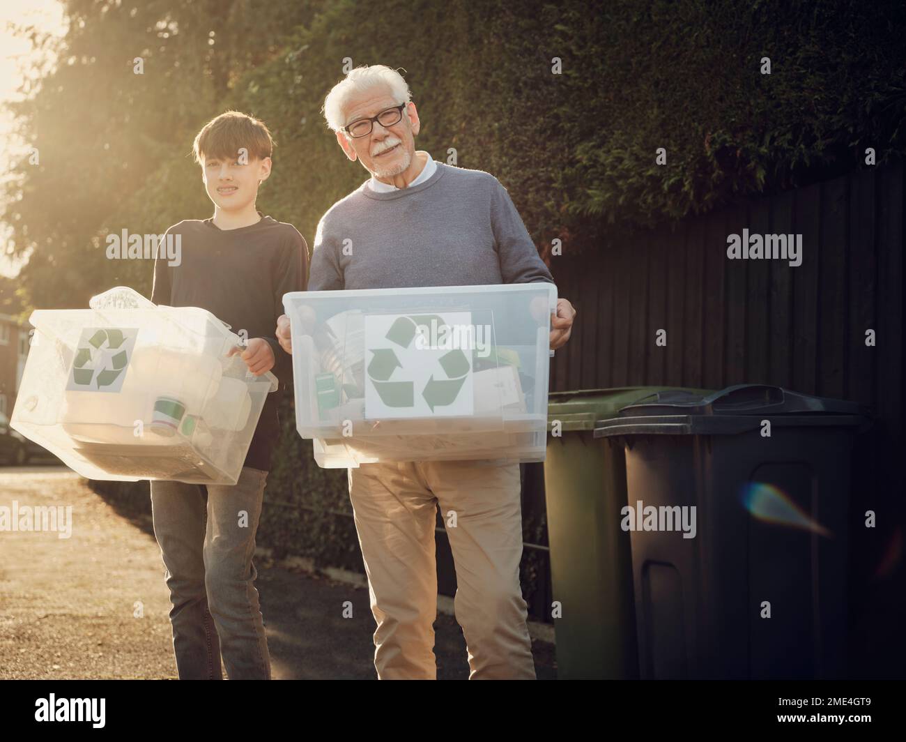 Grand-père et fils debout à l'extérieur transportant des boîtes de recyclage avec des déchets séparés Banque D'Images