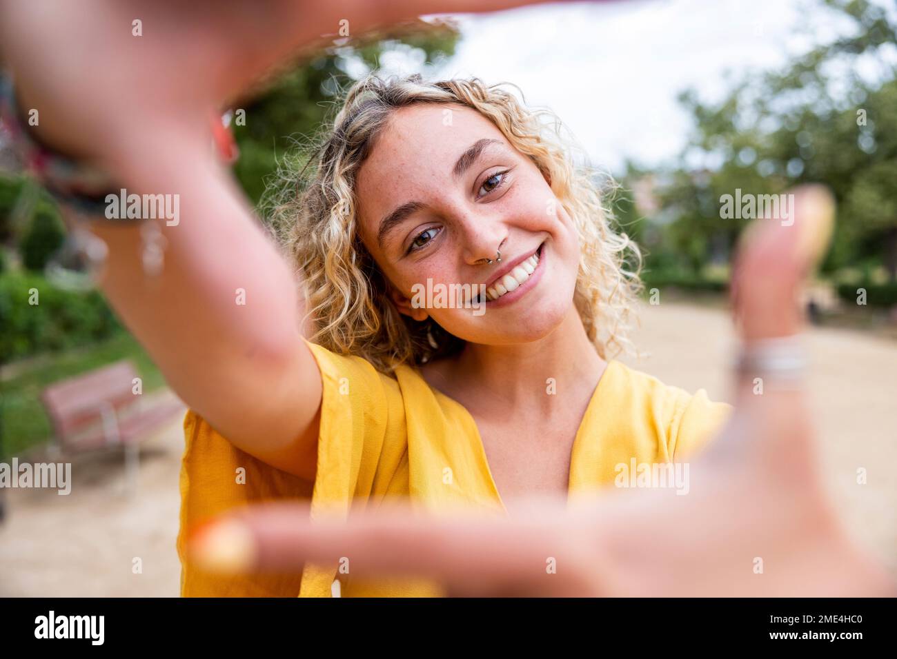 Bonne jeune femme à faire le cadre de doigt dans le parc Banque D'Images