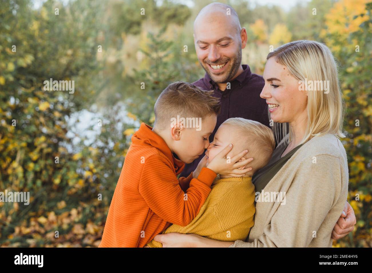 Heureux parents regardant le fils frottant le nez avec le frère en automne Banque D'Images