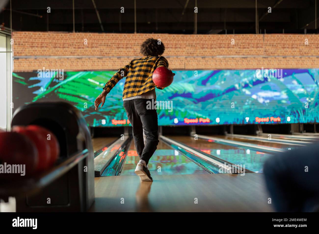 Homme portant une chemise à carreaux jouant à la piste de bowling Banque D'Images