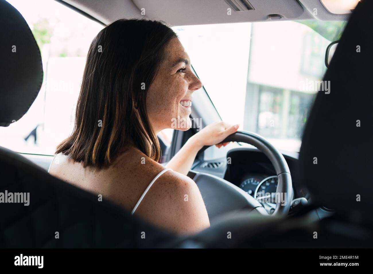 Jeune femme heureuse assise sur le siège conducteur en voiture Banque D'Images