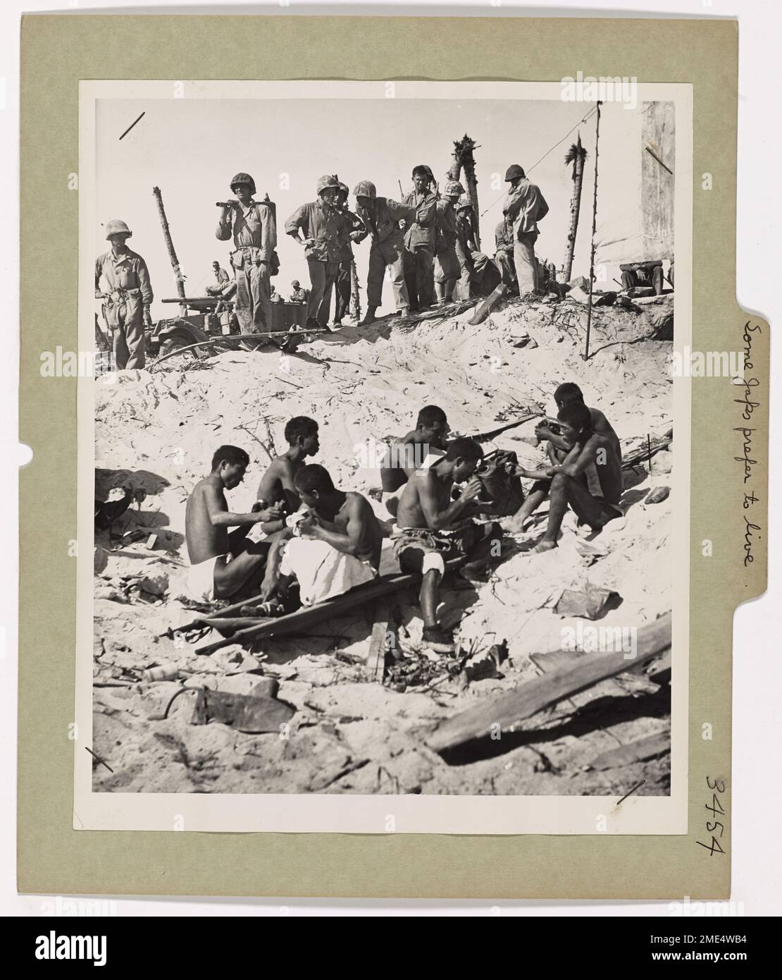 Les prisonniers de guerre japonais, capturés lors de la bataille sur l'île d'Engebi dans l'atoll d'Eniwetok, attendent d'être transférés dans un transport d'assaut habité par les garde-côtes. Ils sont vus blottis ensemble sur la plage, se préparant pour le transport après leur capture par les Marines américains. Banque D'Images