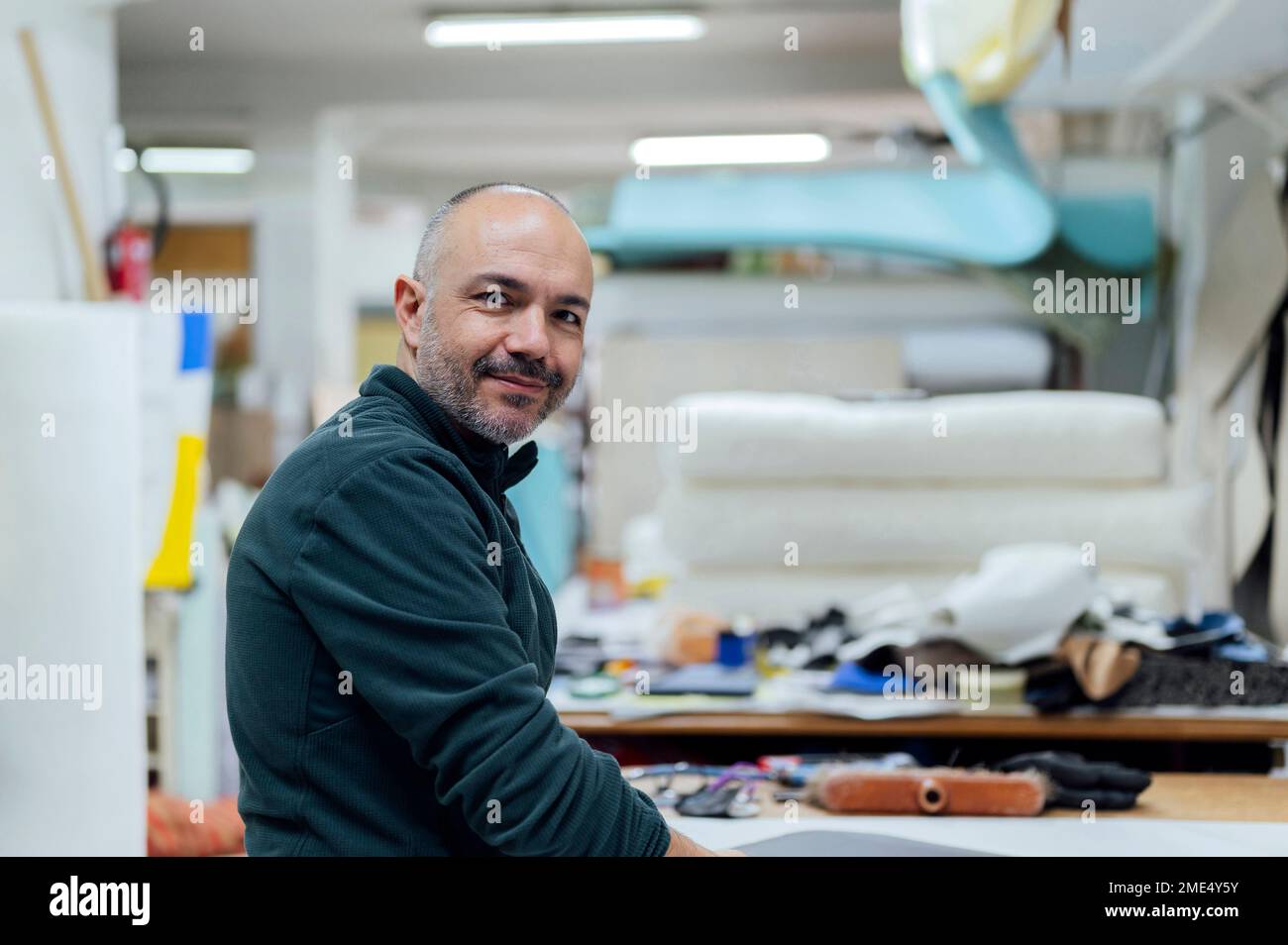 Un artisan souriant dans un atelier de sellerie Banque D'Images