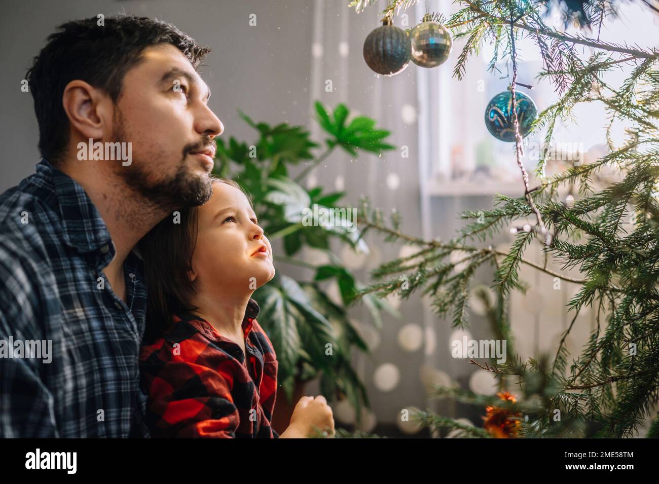 Père et fils regardant l'arbre de Noël décoré Banque D'Images