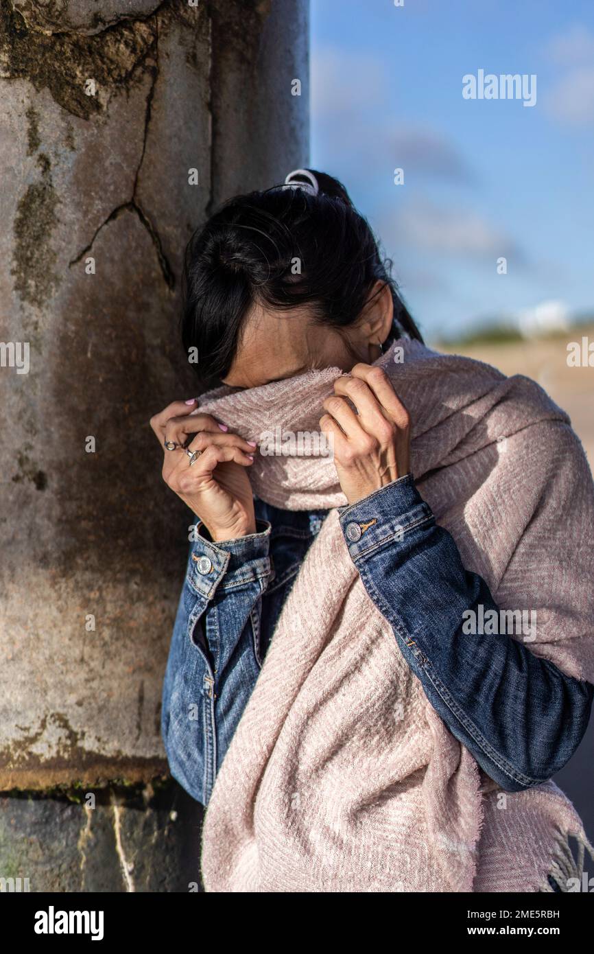Portrait d'une femme timide couvrant son visage avec un foulard Banque D'Images