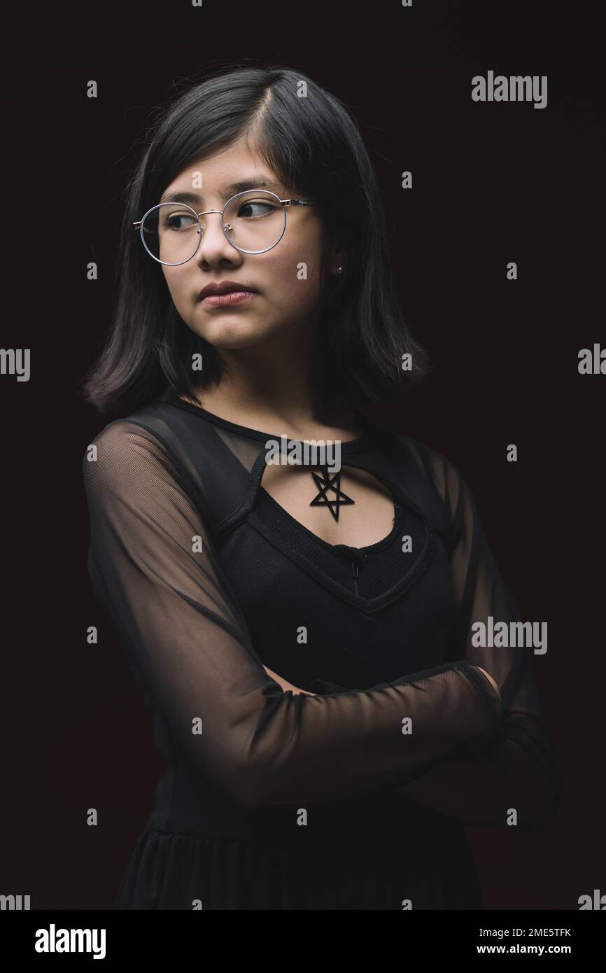 portrait de fille de 12 ans isolé sur fond rouge et portant des lunettes Banque D'Images