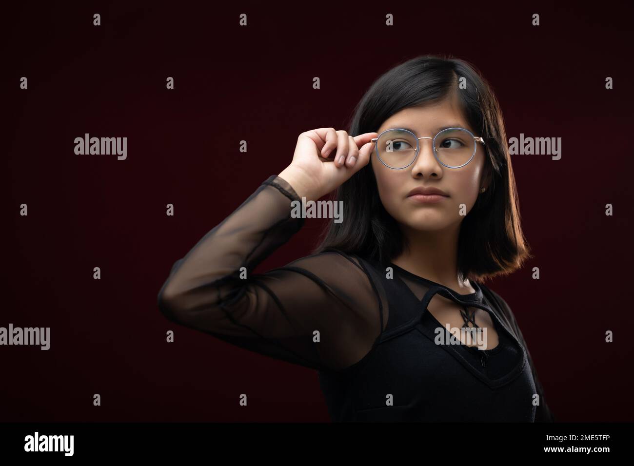 portrait de fille de 12 ans isolé sur fond rouge portant gla Banque D'Images