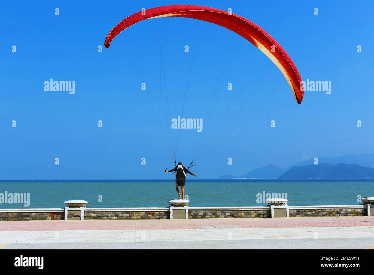 un homme se tient sur un parapet et tente de voler avec un parachute Banque D'Images