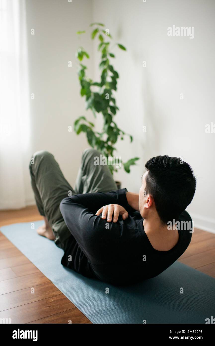 Jeune homme s'entraînant sur Yoga Mat à la maison Banque D'Images