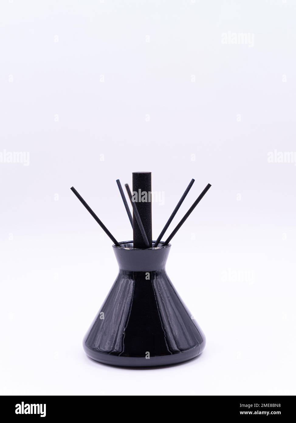 Bâtonnets d'arôme en bois dans un flacon en verre rempli de substance liquide parfumée isolée sur fond blanc, vue latérale Banque D'Images