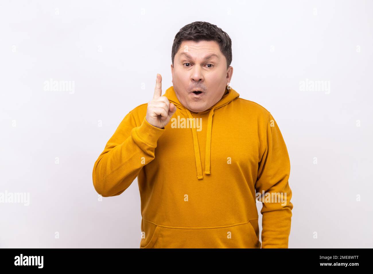 Portrait d'un homme d'âge moyen souriant intelligent pointant du doigt vers le haut, a une bonne idée de plan de génie, d'inspiration et de créativité, en portant un sweat à capuche de style urbain. Studio d'intérieur isolé sur fond blanc. Banque D'Images