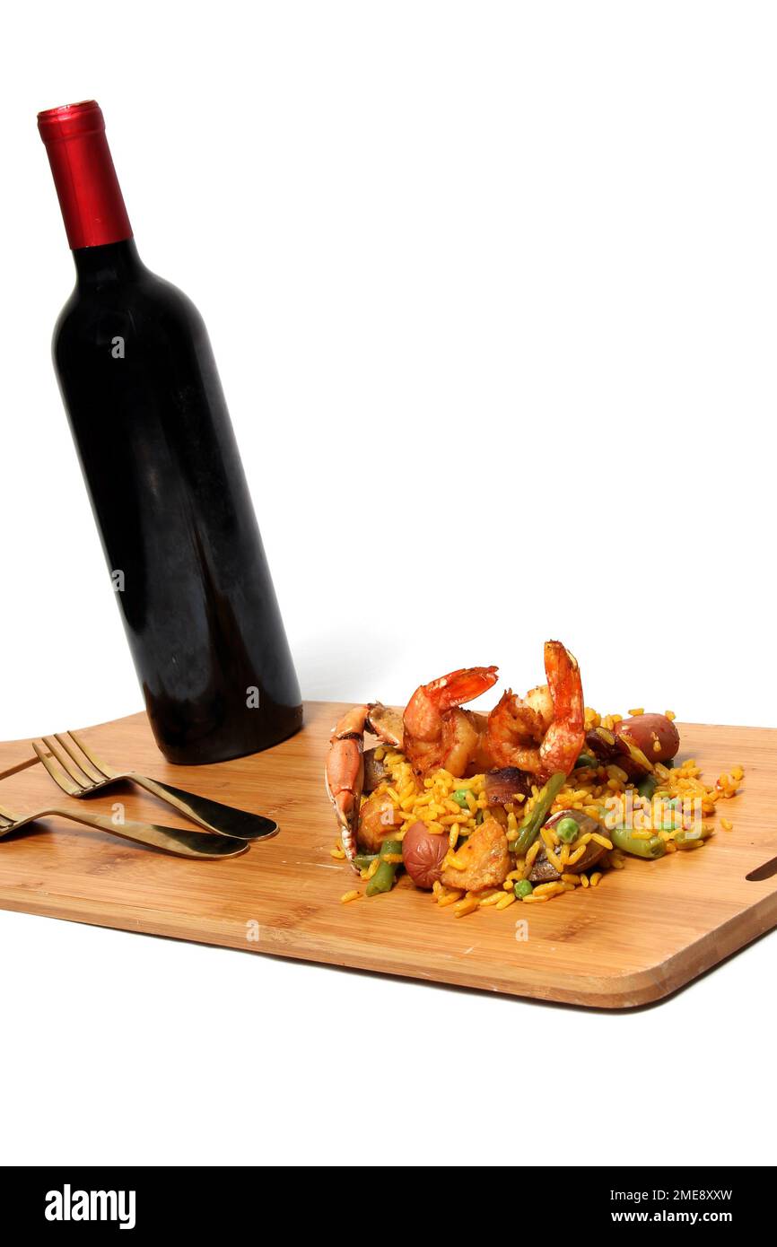 Riz traditionnel paella de Valence Espagne, fait avec des coquillages safran, des crevettes et des légumes servis sur une planche de bois accompagnée de vin rouge Banque D'Images