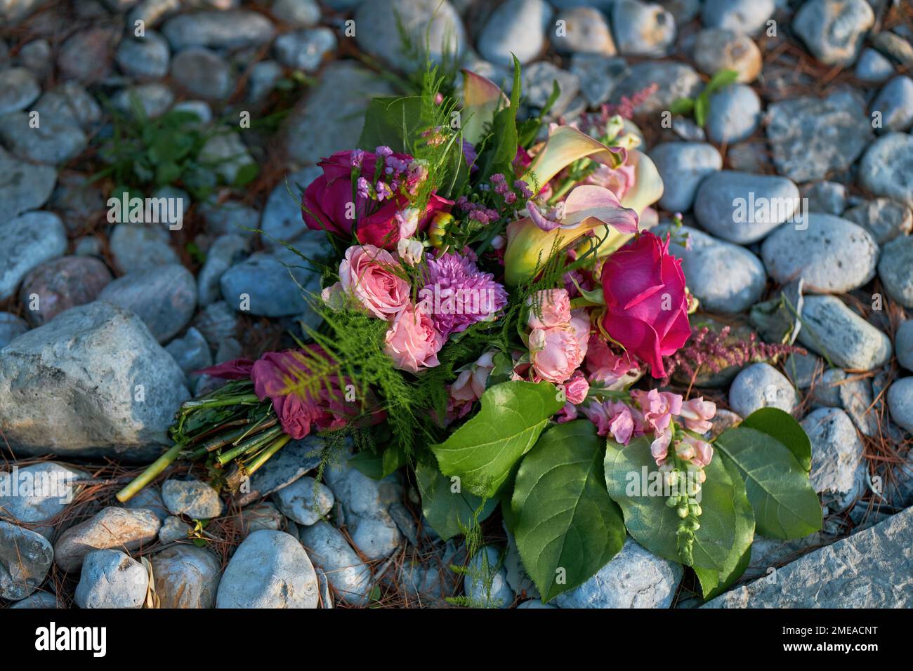 Fleurs de mariage, bouquet de mariée avec roses et lys sur un fond de galets et de rochers Banque D'Images