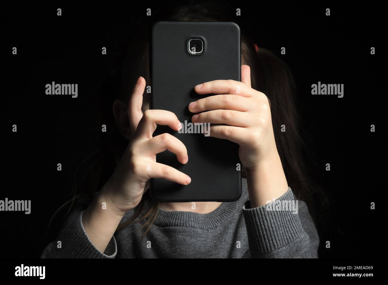 Un grand smartphone dans les mains des enfants, parce que le visage n'est pas visible. Enfant gadget dépendance et insomnie, problèmes psychologiques Banque D'Images