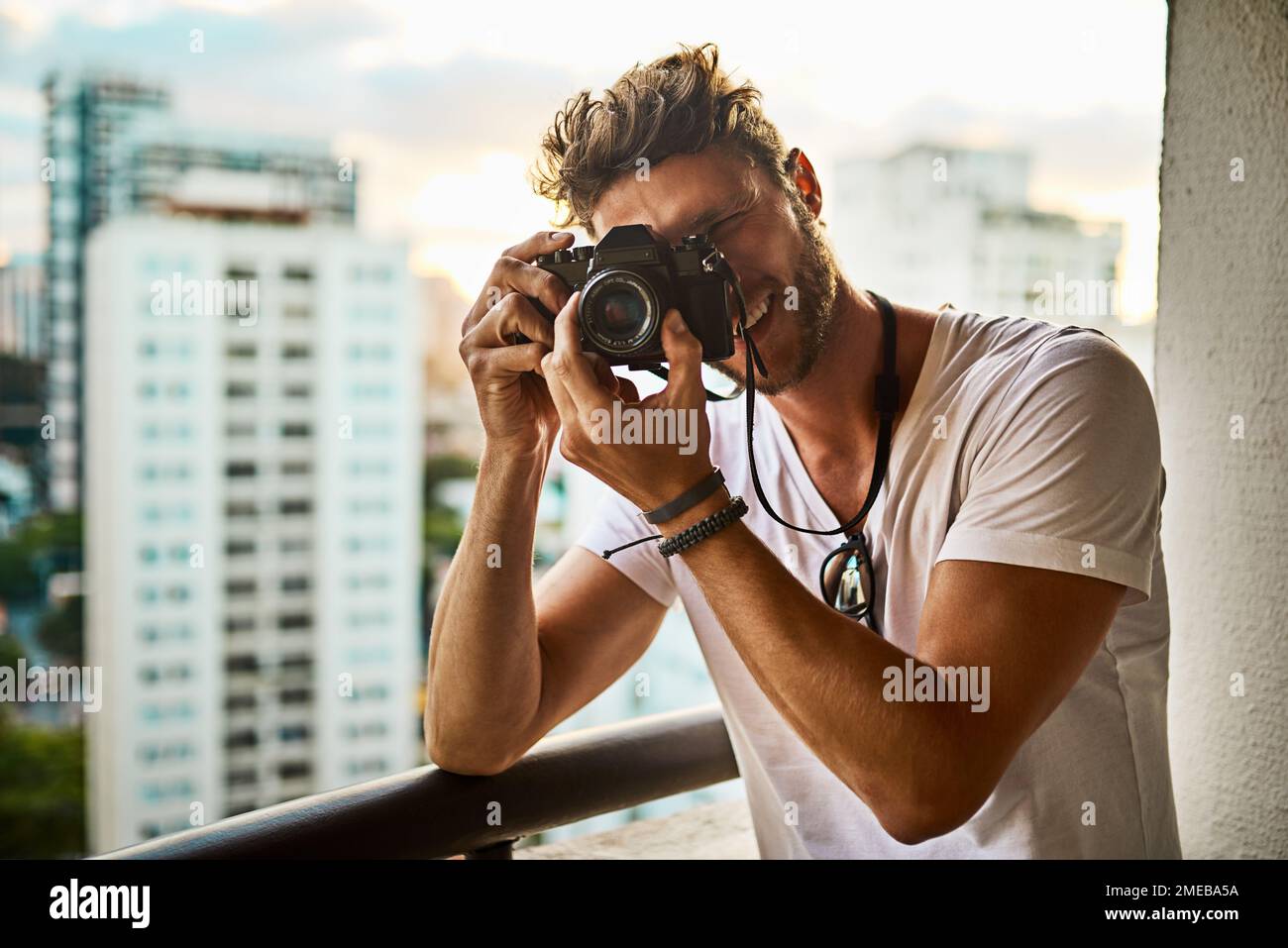 Changez votre façon de regarder les choses. un jeune homme qui prend des photos de la ville avec un appareil photo à l'extérieur. Banque D'Images