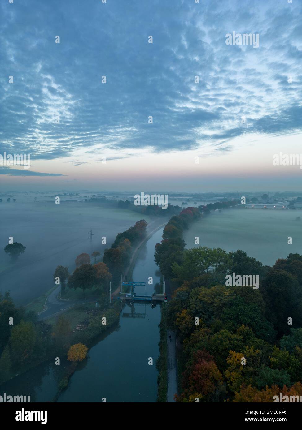 Vue aérienne des arbres brumeux dans le champ au lever du soleil coloré dans la brume d'automne. Paysage coloré avec forêt dans les nuages bas, rivière, prairie dans le brouillard, ciel orange avec soleil le matin à l'automne. Vue de dessus. Nature. Photo de haute qualité Banque D'Images