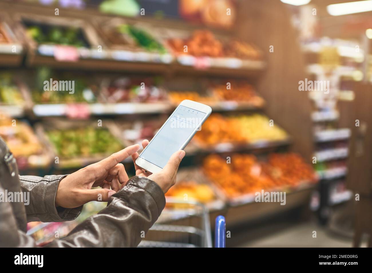 Gérer ses achats avec une application mobile. une femme utilisant un téléphone mobile dans une épicerie. Banque D'Images