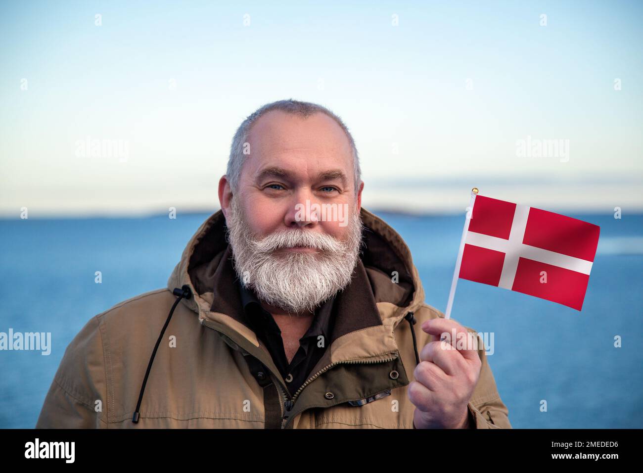 Homme détenant le drapeau du Danemark. Portrait d'un homme âgé avec un drapeau danois national. Visitez le concept du Danemark. Homme plus âgé de 55 60 ans voyageant en hiver Banque D'Images