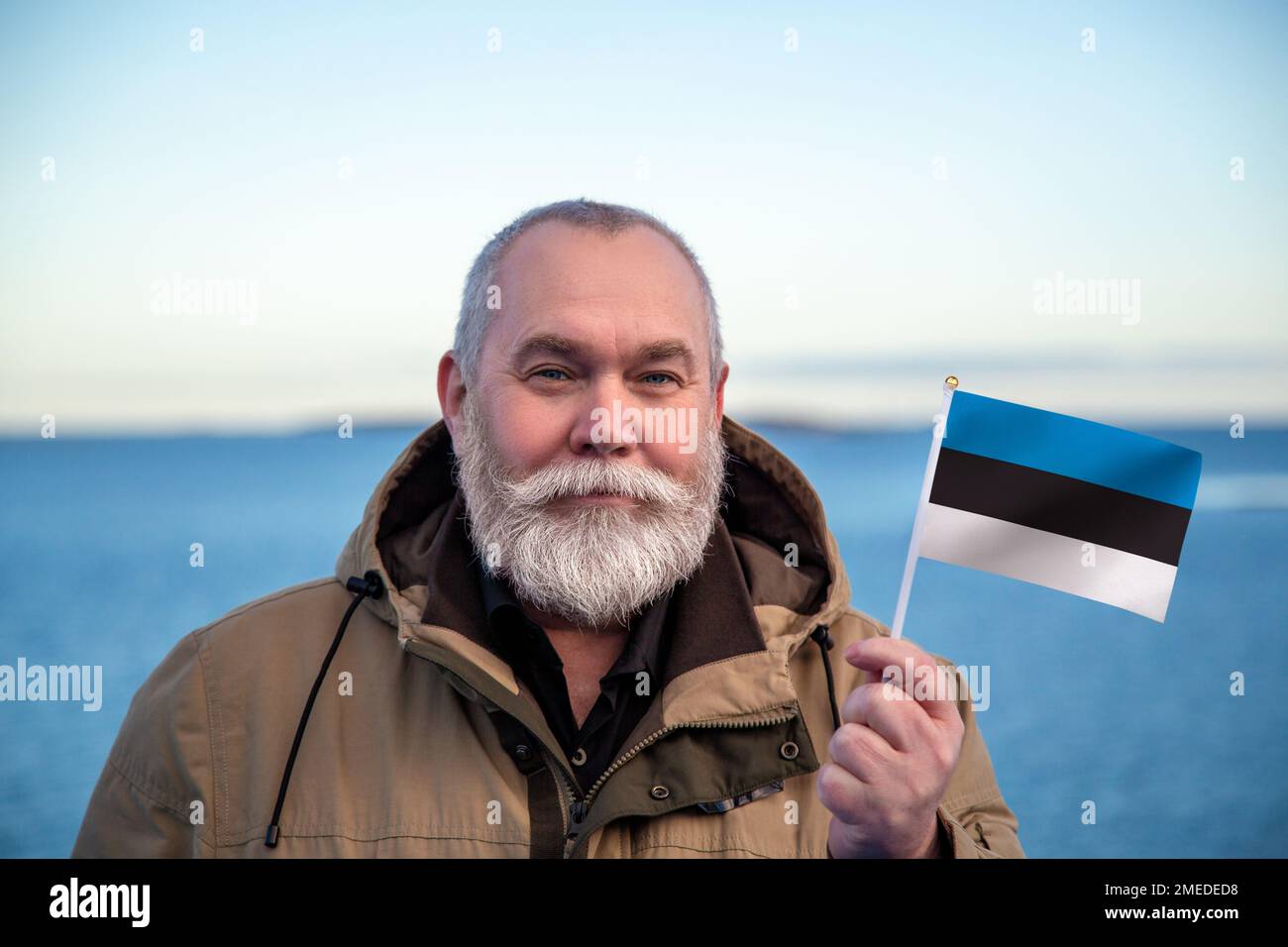 Homme détenant le drapeau de l'Estonie. Portrait d'un homme plus âgé avec un drapeau national estonien. Visitez concept Estonie. Homme plus âgé de 55 60 ans voyageant en hiver Banque D'Images