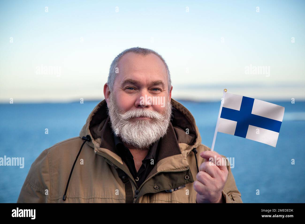 Homme portant le drapeau de la Finlande. Portrait d'un homme âgé avec un drapeau national finlandais. Visitez Finland concept. Homme plus âgé de 55 60 ans voyageant en hiver Banque D'Images