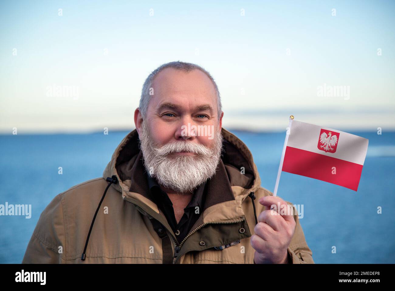 Homme tenant le drapeau de la Pologne. Portrait d'un homme plus âgé avec un drapeau national polonais. Visitez le concept de Pologne. Homme plus âgé de 55 60 ans voyageant en hiver Banque D'Images