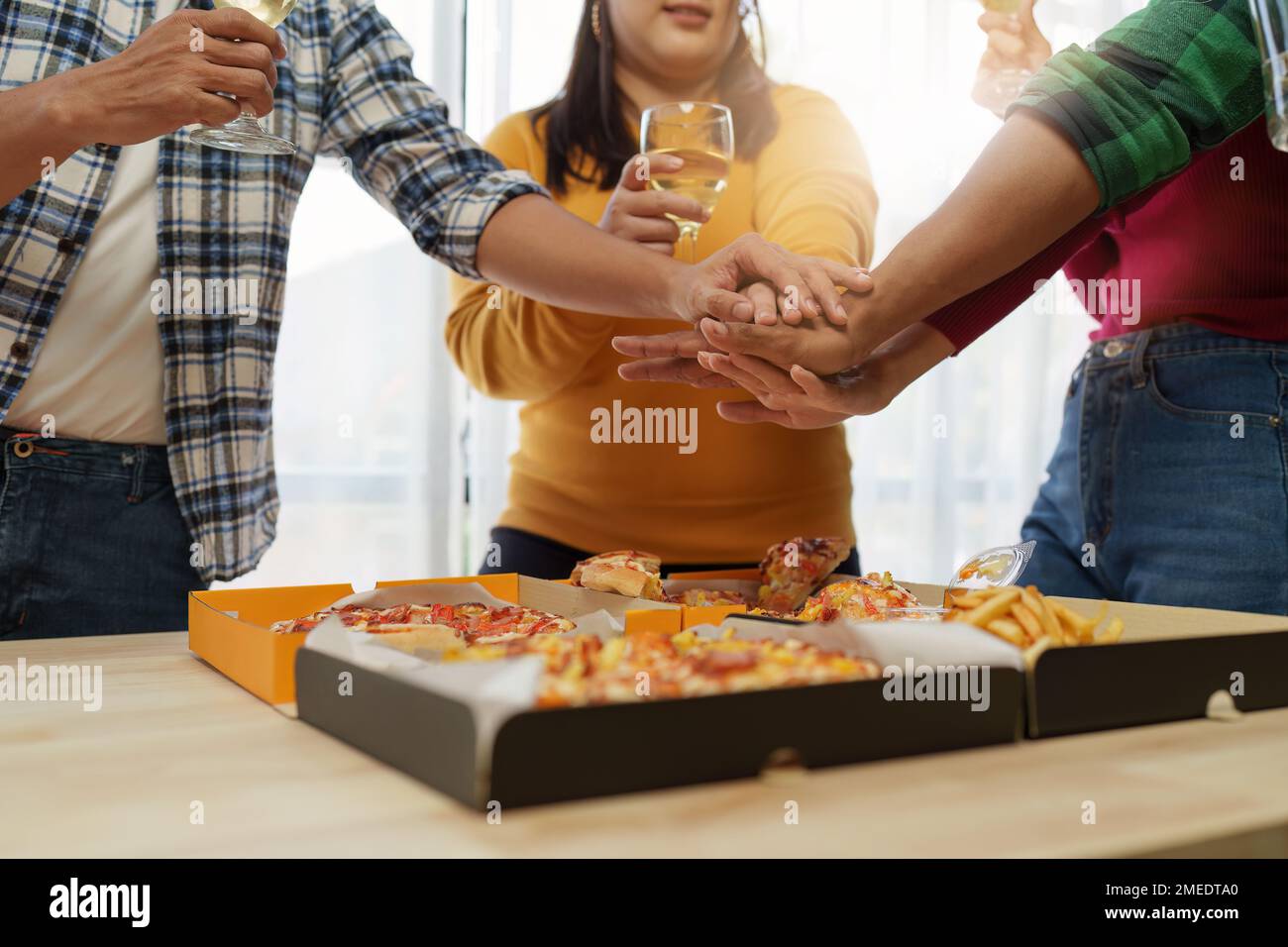 Les amis à la fête d'anniversaire se trinquent avec des verres de champagne et de pizza, en appréciant les vacances de Noël, pizza sur la table. Fête des fêtes. Banque D'Images