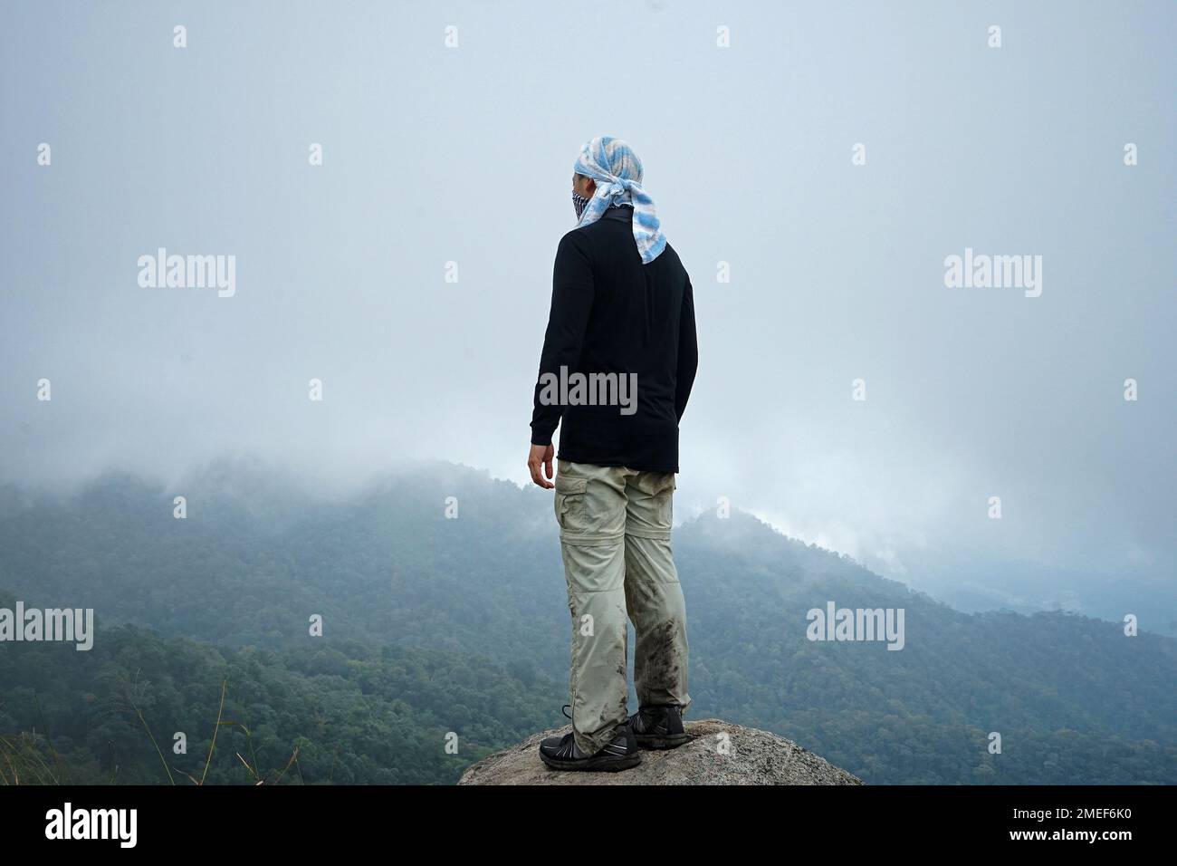 Un homme qui monte sur la crête de montagne verte avec un ciel bleu nuageux Banque D'Images