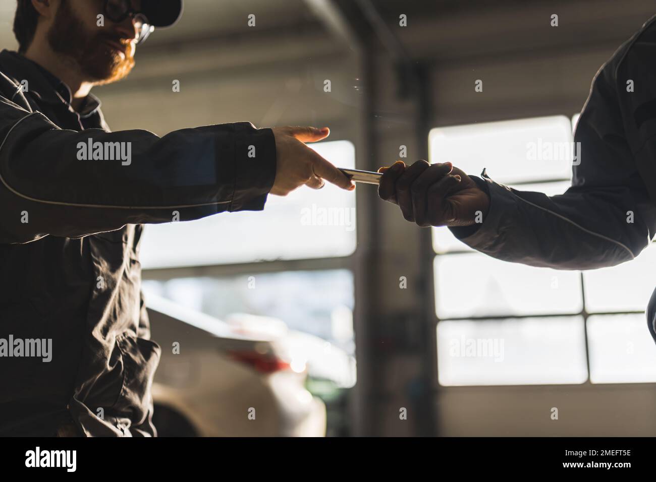 Un mécanicien prenant les clés de sa voiture de son collègue - atelier de réparation automobile vue à angle bas. Photo de haute qualité Banque D'Images Un mécanicien prenant les clés de sa voiture de son collègue - atelier de réparation automobile vue à angle bas. Photo de haute qualité Banque D'Images