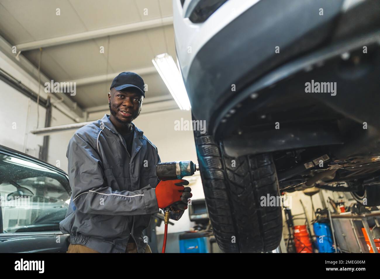 Le mécanicien qui change les pneus à l'aide d'une clé électrique est soulevé pour un processus régulier. Photo de haute qualité Banque D'Images