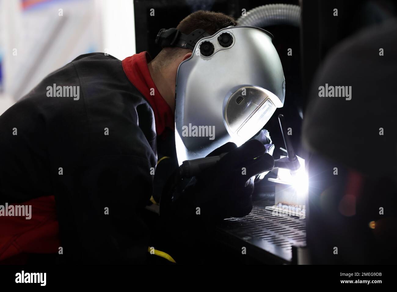 Un travailleur industriel sourie des pièces en acier sur un casque. Mise au point sélective. Banque D'Images