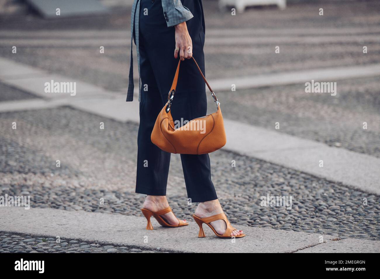 Milan, Italie - 24 février 2022: Femme en pantalon chic et sandales brunes à talons hauts avec sac à main. Banque D'Images