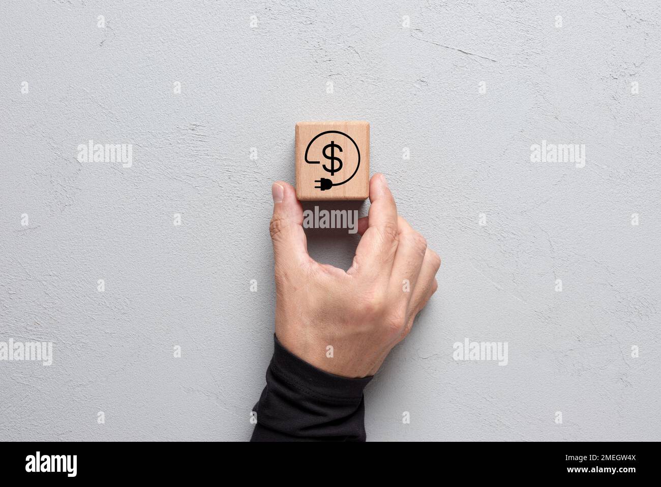 Réduction des coûts d'électricité. Économies d'énergie. La main masculine place un cube avec un symbole d'économie d'énergie ou d'électricité. Banque D'Images