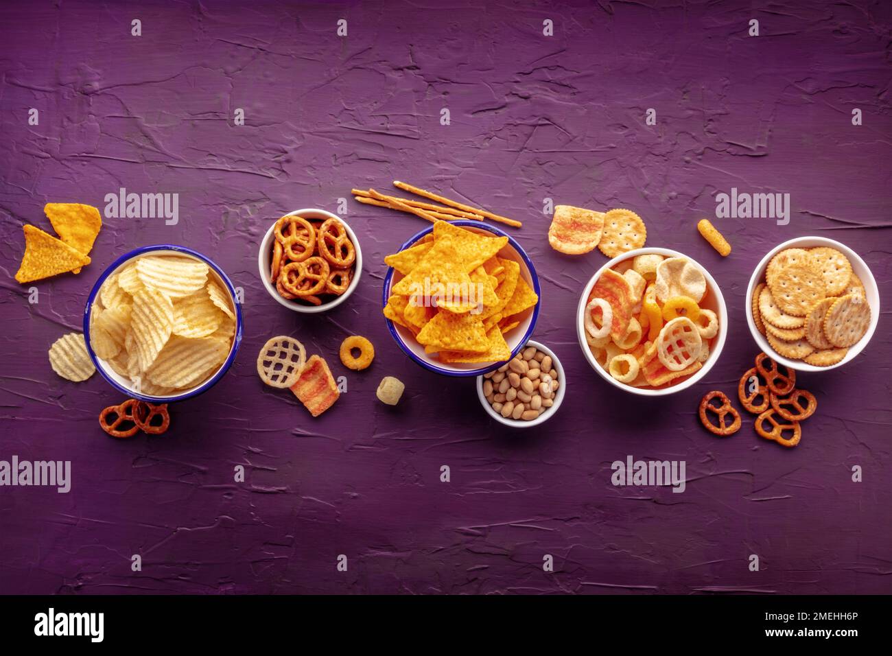 En-cas salés, fond de lit plat avec espace de copie. Repas de fête sur le violet. Chips de pommes de terre et de tortilla, craquelins salés et autres hors-d'œuvre Banque D'Images