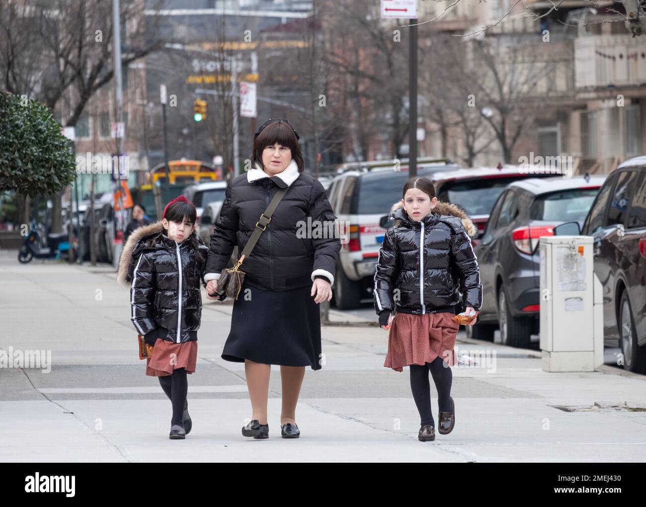 Une mère et 2 filles qui sont vêtues de la même façon, probablement parce que les jupes sont des uniformes d'école. À Brooklyn, New York. Banque D'Images