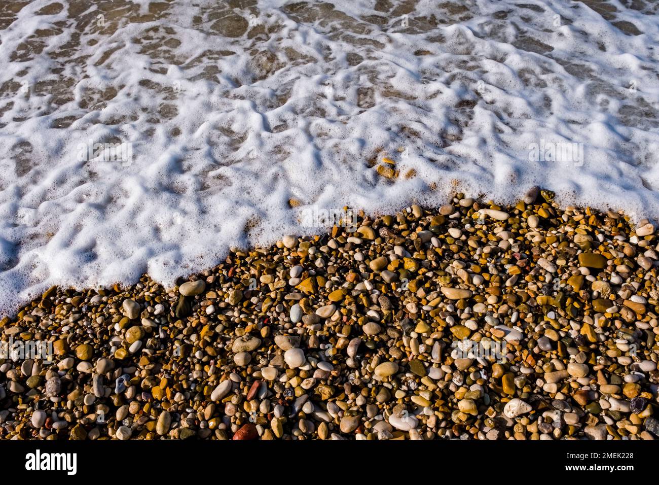Pierres colorées et spray sur la plage de Capo Bianco. Banque D'Images