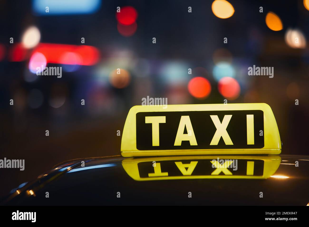 Attention sélective sur le panneau de taxi sur le toit de la voiture contre la rue animée de la ville la nuit. Banque D'Images