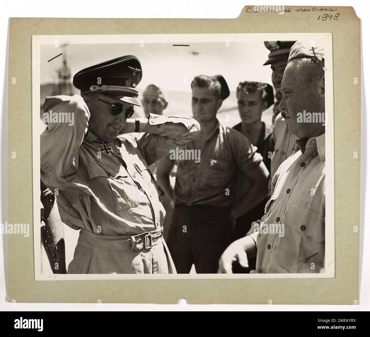 Un officier allemand retire sa croix de fer pour la montrer aux curieux garde-côtes américains, qui l'avaient capturé avec d'autres prisonniers allemands amenés aux États-Unis depuis l'Afrique du Nord. L'image met en évidence la rencontre entre la Garde côtière et les prisonniers de guerre. Banque D'Images