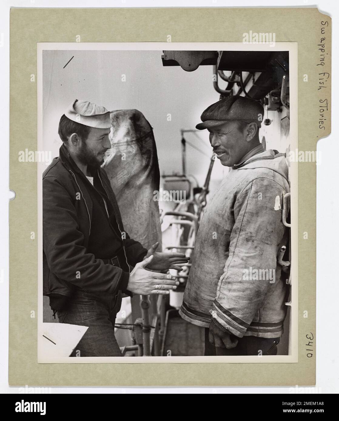 Le gardien de la côte Wesley Parker entretient une conversation amicale sur la pêche avec un esquimau, soulignant l'échange culturel pendant les missions de la Garde côtière dans l'Arctique. Banque D'Images