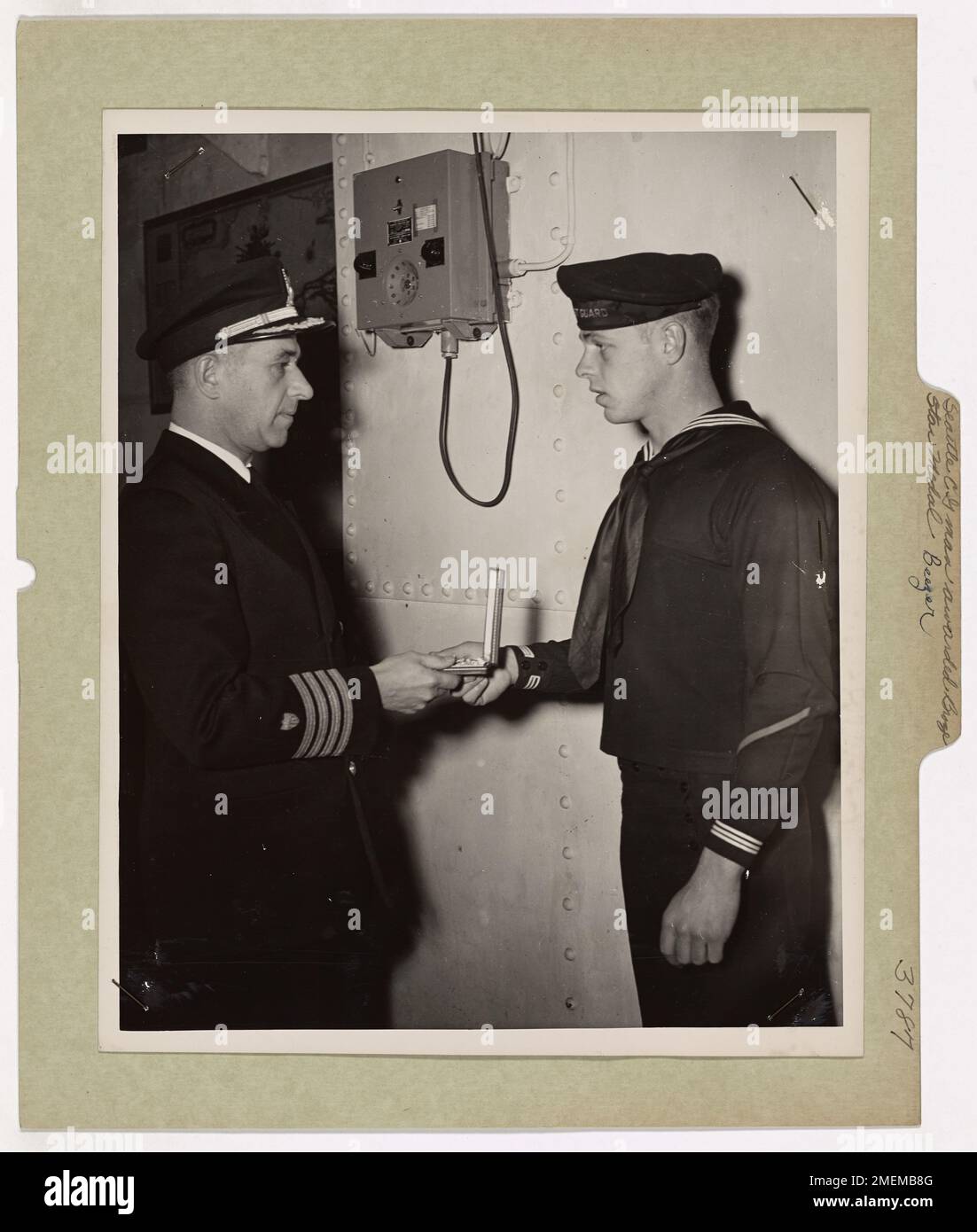 Le garde-côtes Earl F. Beezer, Jr. De Seattle, Washington, reçoit la médaille d'étoile de bronze du capitaine Frank A. Leamy pour ses actions héroïques lors de l'invasion initiale de la France lors de la seconde Guerre mondiale. La pensée rapide et la bravoure de Beezer ont aidé à sauver la vie de sept camarades sous le feu ennemi. Banque D'Images