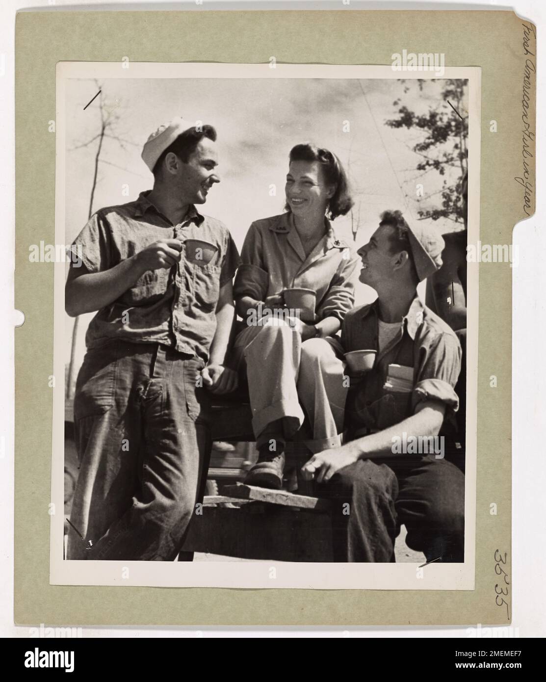 Des gardes côtiers discutent avec Mlle Ida Helbig, membre de la Croix-Rouge, à Hollandia. Après un an dans le Pacifique, ces hommes étaient ravis de parler à une américaine, reflétant le soulagement émotionnel de recevoir une communication familière en temps de guerre. Banque D'Images
