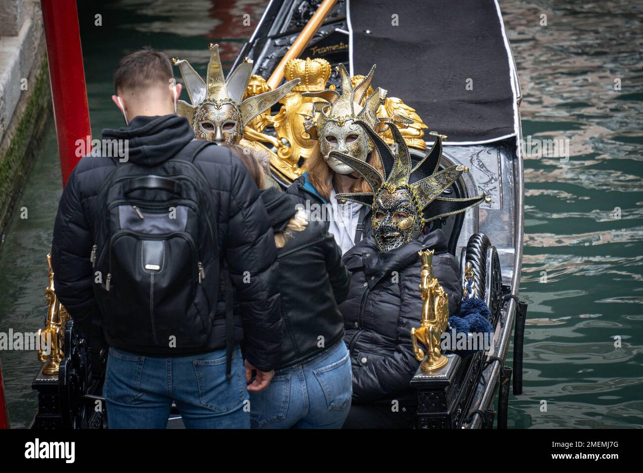 Télécabine avec trois touristes portant des masques de carnaval assis dans elle et deux autres touristes faisant des photos d'eux à Venise, Italie Banque D'Images