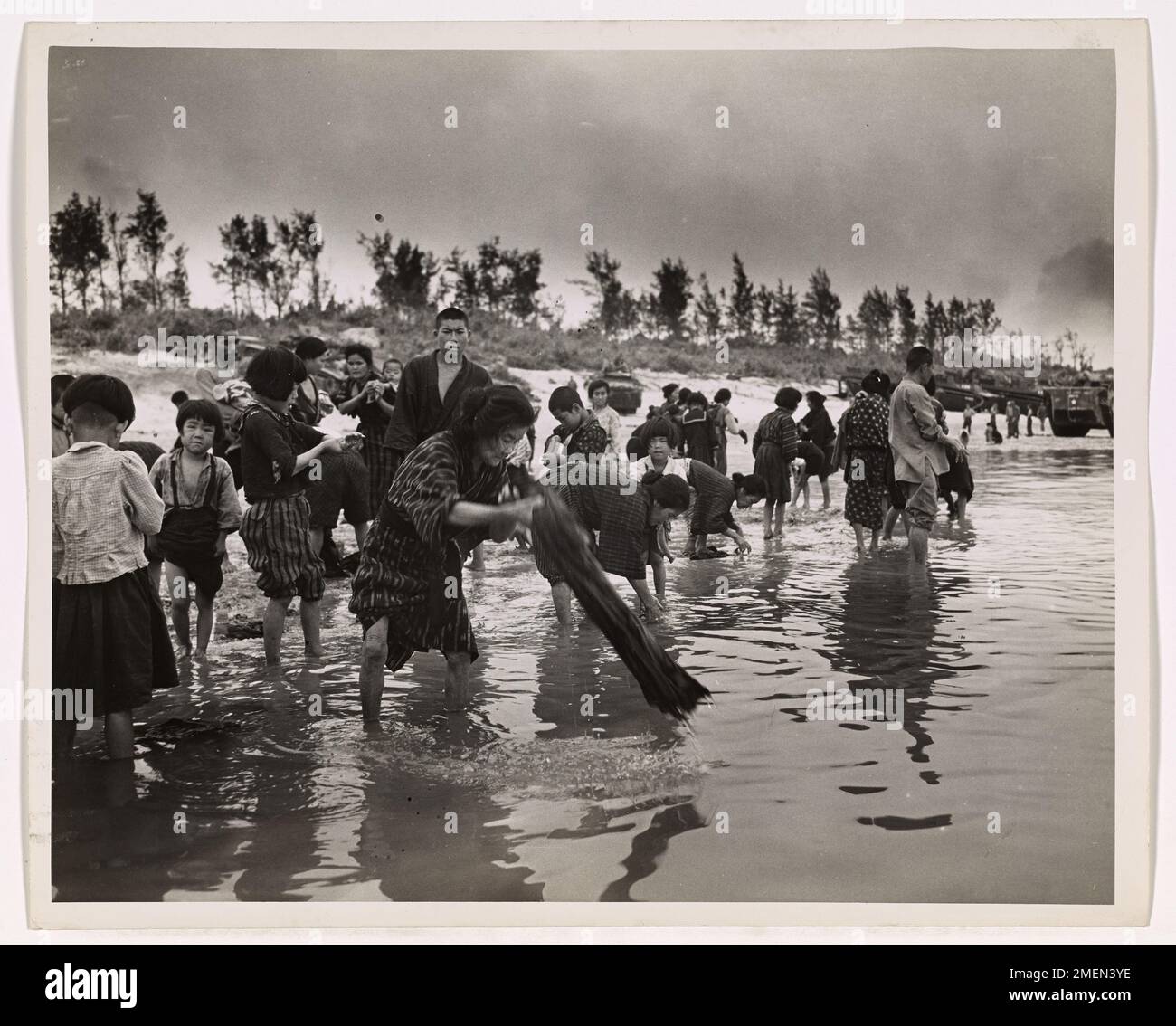 Heure de nettoyage dans le camp de réfugiés de Shima IE. Les habitants d'IE Shima sont escortés tous les jours à la plage pour laver leurs vêtements et se baigner. Ces civils sont gardés sous la garde des forces américaines dans un camp de réfugiés. IE Shima, une île importante près d'Okinawa, est tombée à une force amphibie américaine de soldats, de gardes-côtes et d'hommes de la Marine pendant l'poussée dans les Ryukyus. Banque D'Images