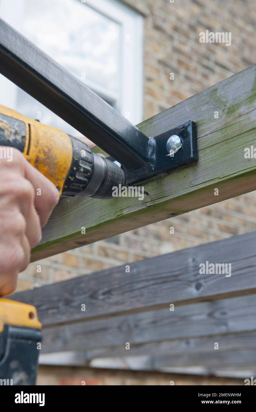 Faire un auvent de patio de bricolage - trou de perçage pour un oeil de vigne sur une pergola en bois Banque D'Images