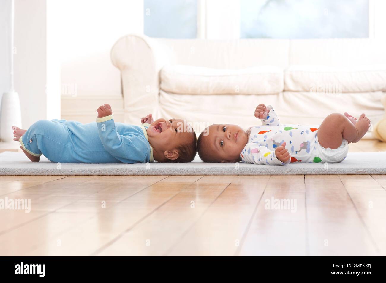 Deux bébés garçons allongé sur le dos sur un tapis, 4 mois Banque D'Images