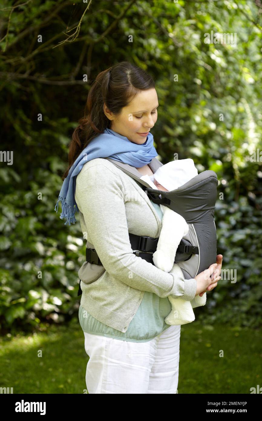 Mère portant bébé garçon (3 semaines) dans une élingue Banque D'Images