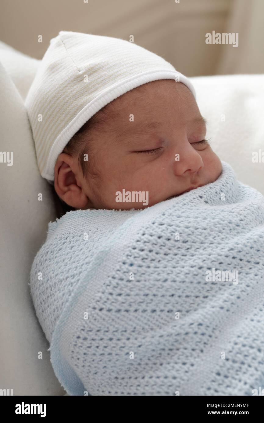 Bébé garçon endormi (3 semaines) enveloppé dans une couverture portant un chapeau, gros plan Banque D'Images