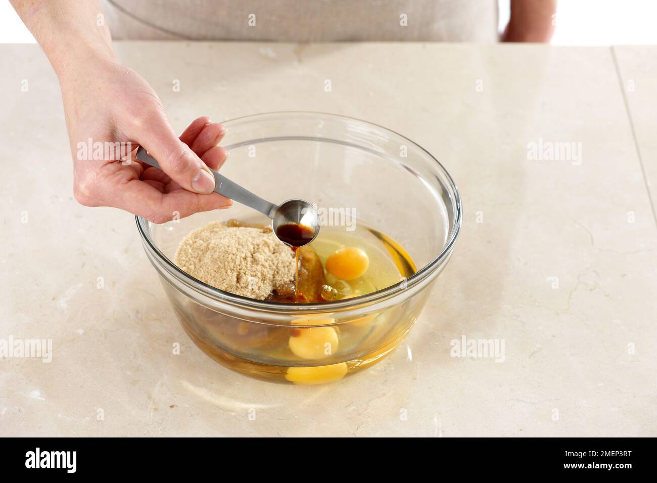 Faire du gâteau au Carrot, en ajoutant de l'extrait de vanille à l'huile, des œufs et du sucre brun clair Banque D'Images