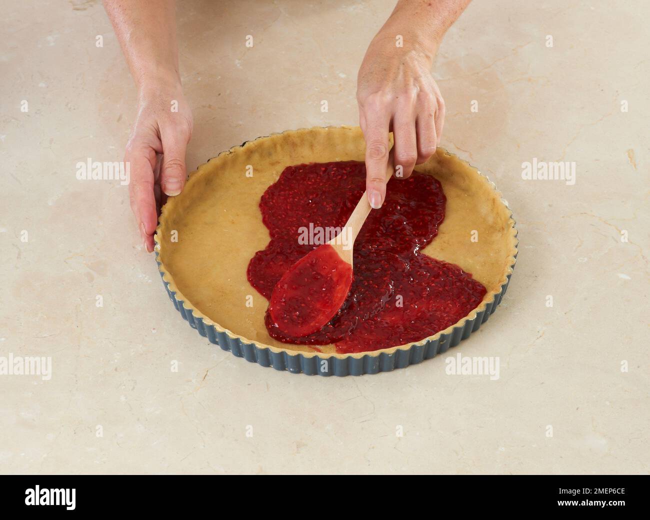 Préparation d'une tarte autrichienne traditionnelle, Linzertorte, étalant la garniture de framboise sur une base de pâtisserie Banque D'Images