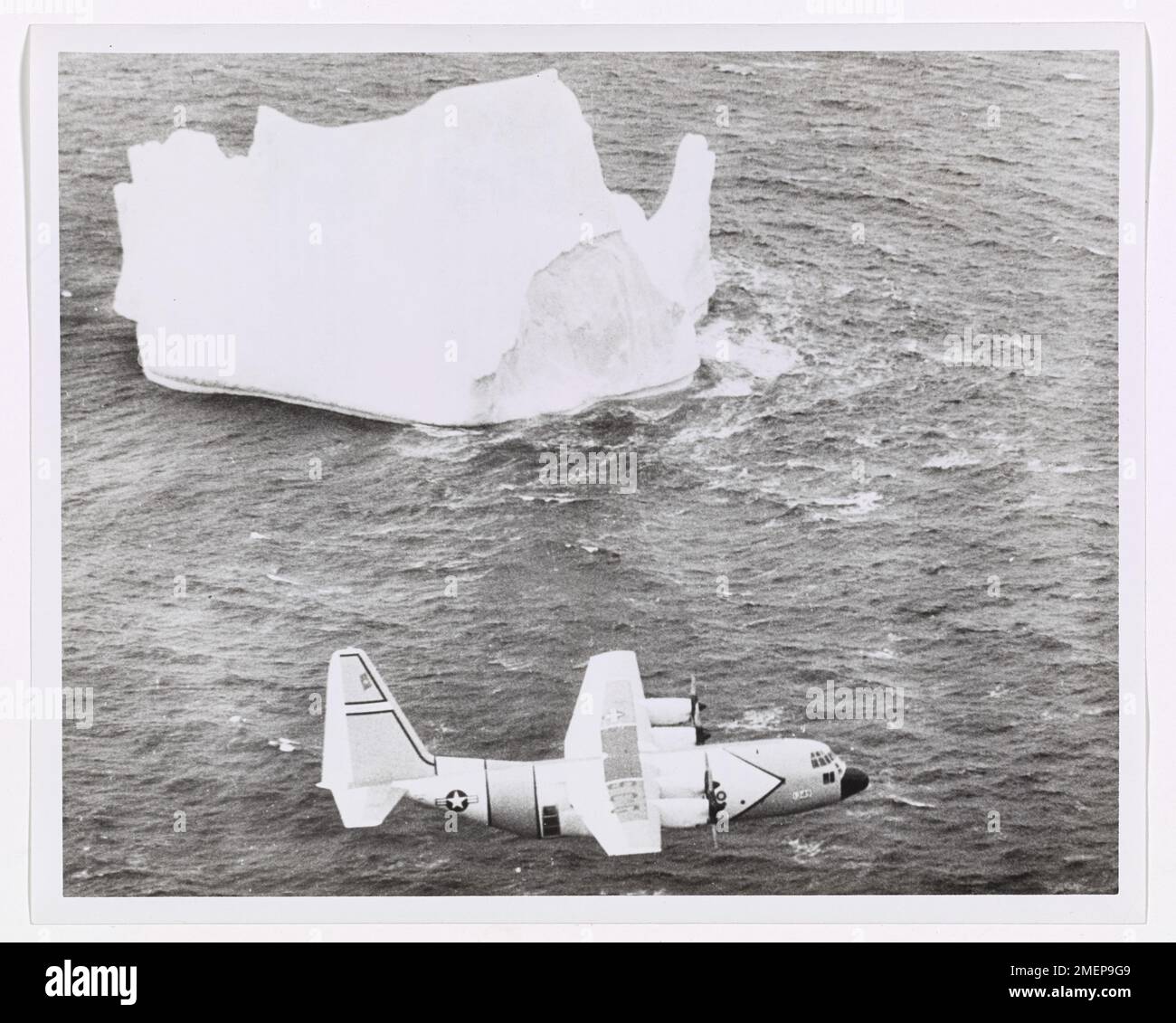 Surveillance des glaces plans de vues massive Iceberg. A ÉTATS-UNIS L'avion de patrouille sur glace Hercules HC-130-B de la Garde côtière suit un énorme iceberg vu seul les Grands bancs au large de Terre-Neuve à travers les puissantes jumelles d'un observateur assis à une fenêtre latérale de l'avion. L'observateur, spécialement formé à la détermination de la taille, de la direction et de la vitesse des bergs, entre dans son journal les observations et les calculs de distance effectués par Radar. Après le vol, son entrée est contrôlée par rapport à la position de Loran obtenue par le navigateur pendant le vol. À partir de ces données, l'emplacement de l'iceberg est dissuasif avec précision Banque D'Images